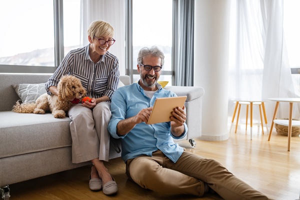 man and woman with a dog sitting and looking at a tablet